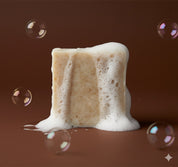 Bar of soap with foam on a brown background