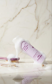 Cosmetic bottle with brush on a marble surface