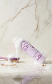 Cosmetic bottle with brush on a marble surface