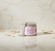 Jar of 'the darkspot slayer' product on a marble surface with gold jewelry.